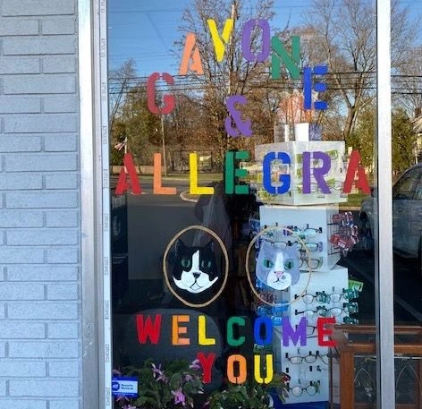 Rockaway Pharmacy window decorated with cat illustrations and “Gavone & Allegra welcome you” lettering